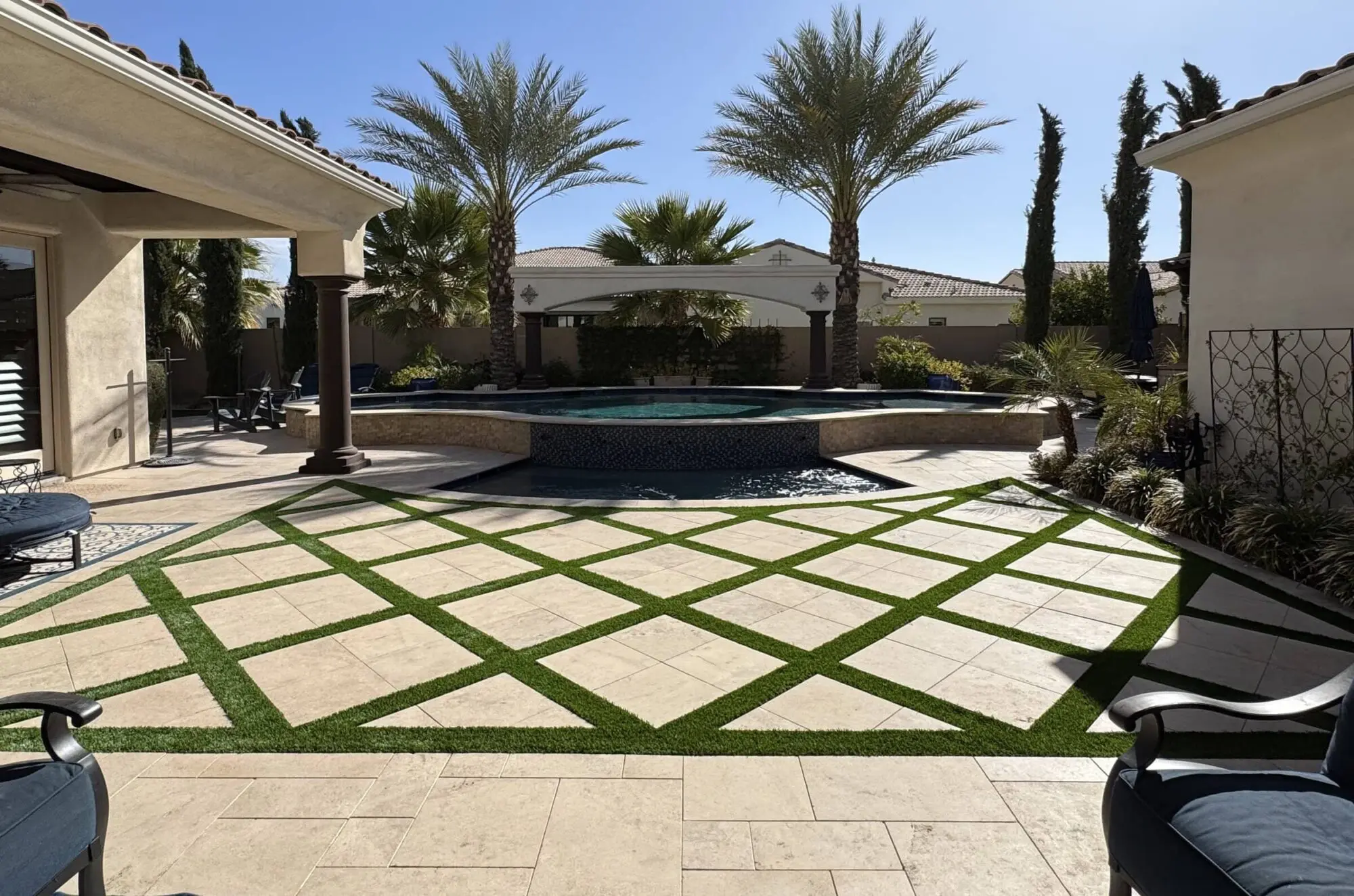 travertine pavers with artificial grass strips in between, at a poolside patio in Phoenix AZ