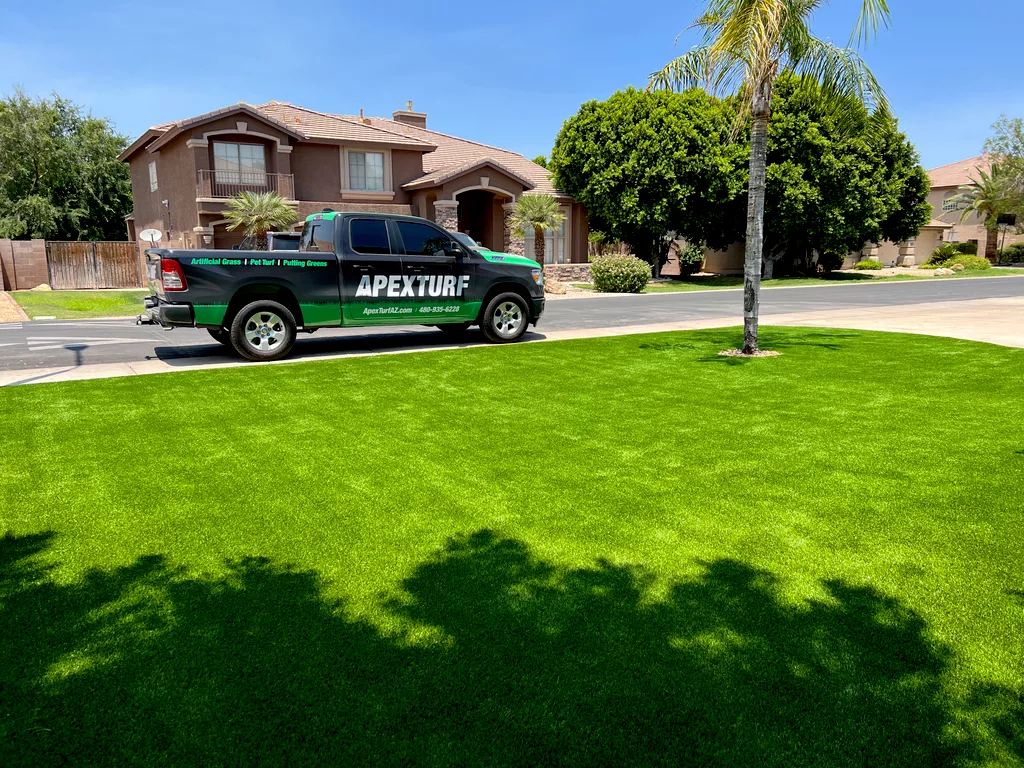 Apex Turf signwritten truck, black and green with APEX TURF written in white letters sits parked in front of a home with a large tucson turf lawn.