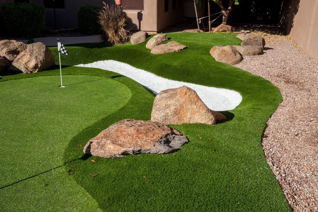 Backyard putting green in Phoenix with a small sand trap and one hole with a checkered hole flag