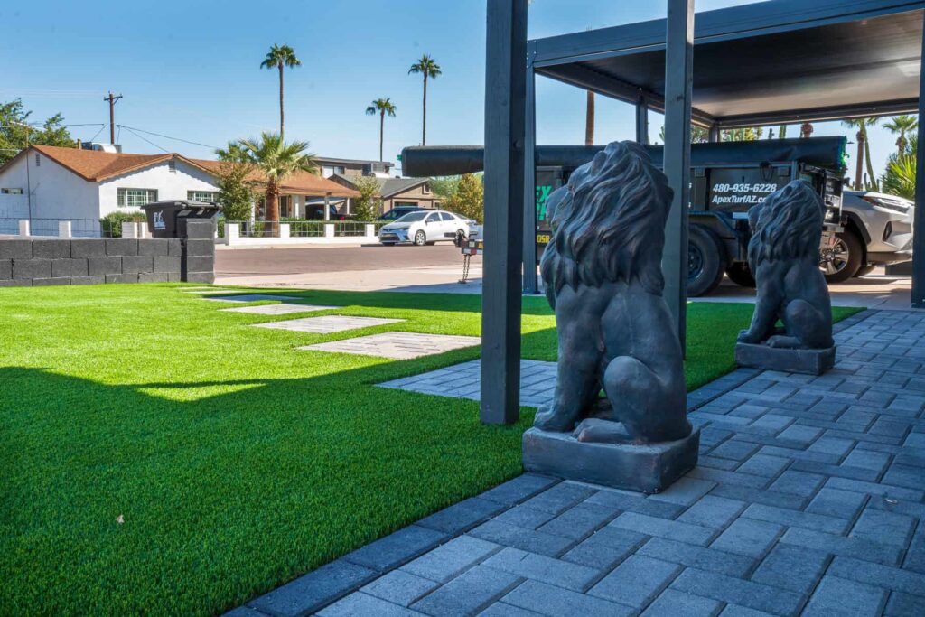 Grey paver front patio with paver squares laid into artificial grass, leading to mailbox