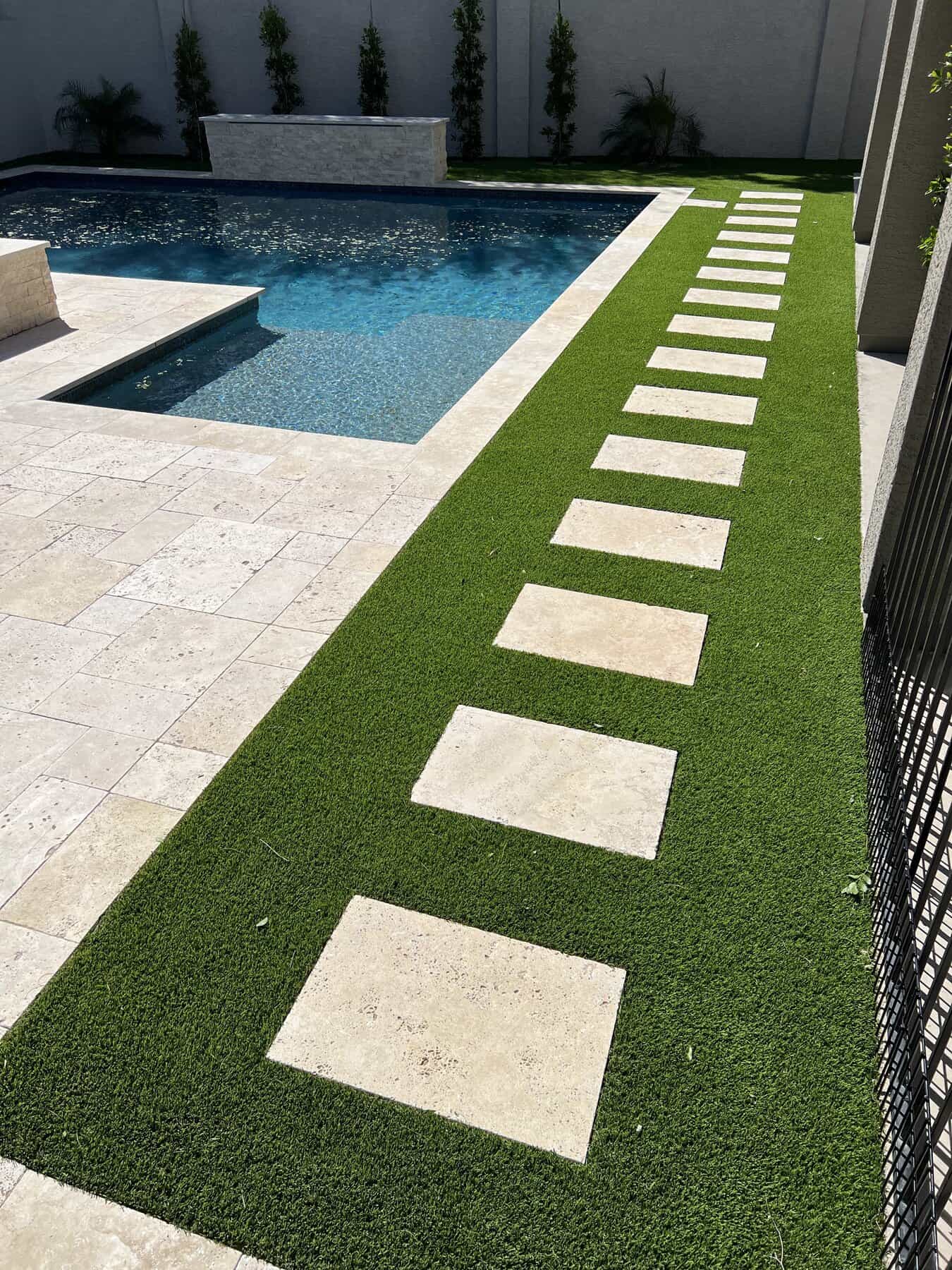 Sqaure pavers with artificial turf installed next to a pool deck in Phoenix AZ.