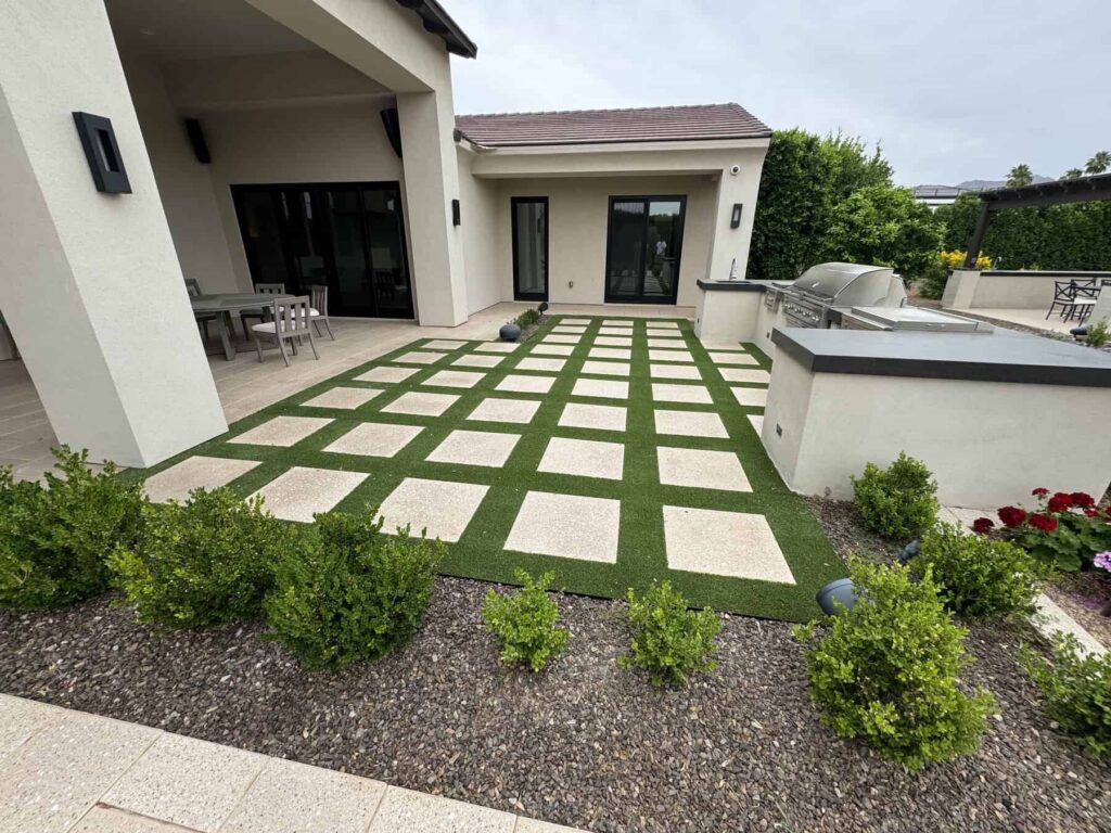 Square travertine paver patio with artificial grass in between