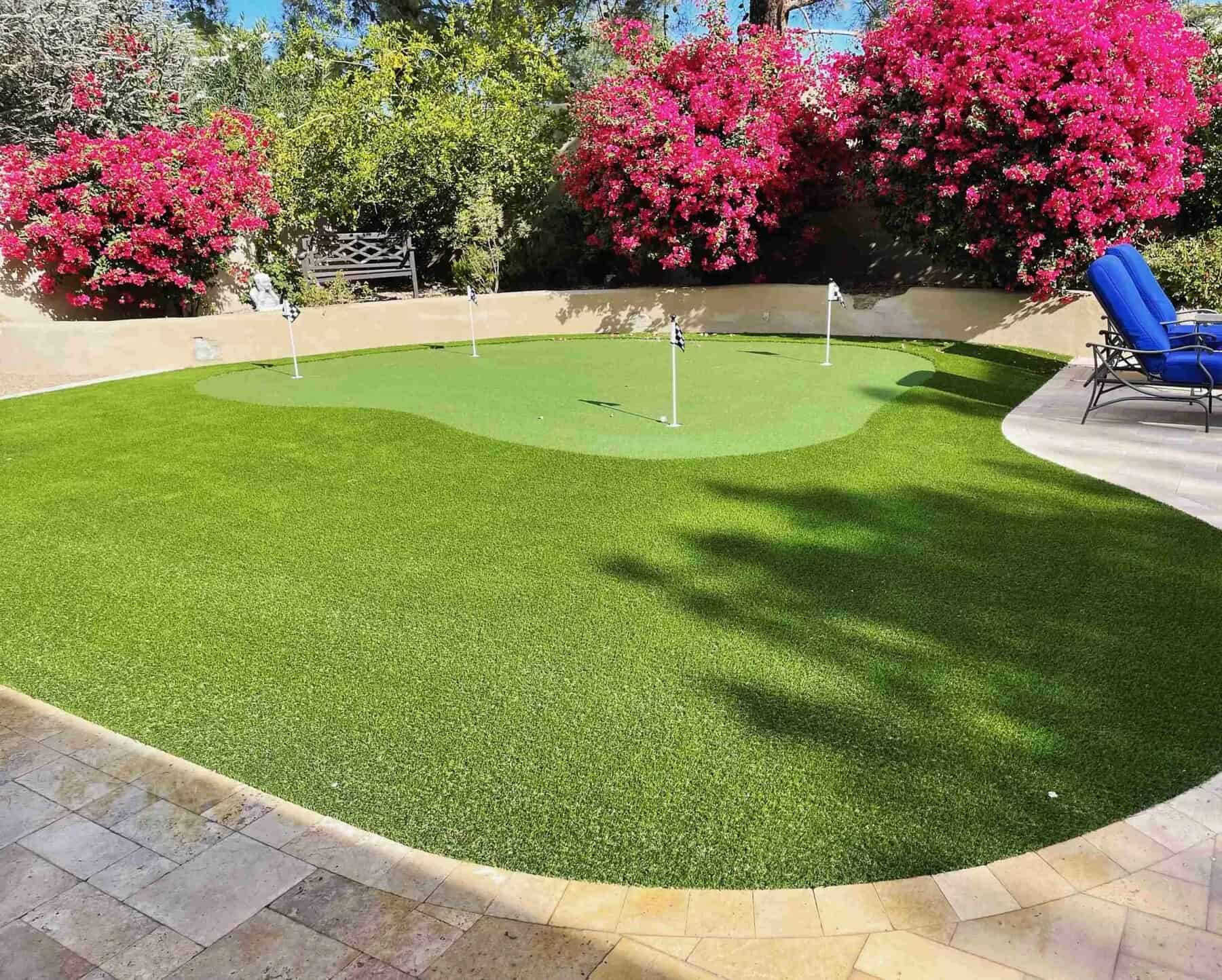 Synthetic grass putting green in Phoenix Arizona. Has fringe area with low pile height artificial grass in the middle. Four hole course with checkered flags marking each hole