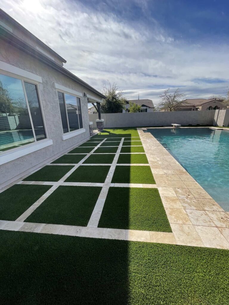 Travertine pavers with artificial grass strips next to a pool at a home in Scottsdale Arizona.