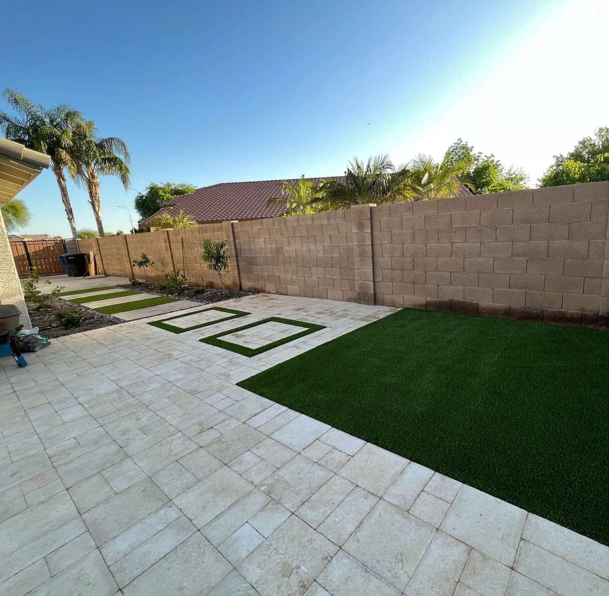 artificial grass and travertine pavers installed next to a pool deck in Chandler az