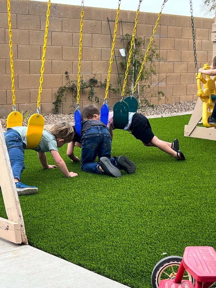 three kids hanging on swings dragging their feet on the playground flooring freshly installed by Apex Turf in Phoenix
