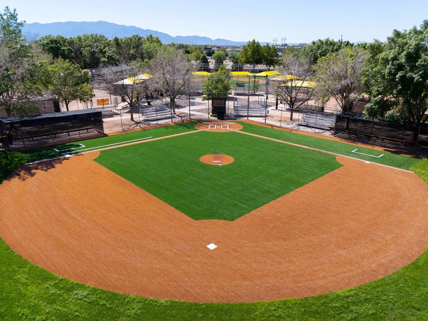 Baseball field with green infield turf and brown outfield turf and basepaths.