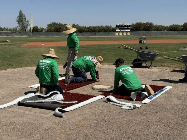 Four Apex Turf sports turf installers working on a new synthetic turf batters box for a baseball facility in Arizona