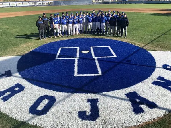 Picture of the new synthetic grass on deck circle in blue astroturf with the "TROJAN" lettering on a white turf background. Valley Christian Trojans baseball team is lined up in uniform behind their new on deck circle. Photo takedn at the Valley Christian Highschool campus in Chandler, Arizona.