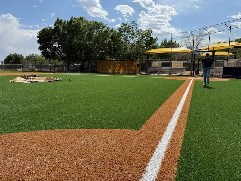 Photo showing the astroturf basepaths in a brown color with a white line at a newly surfaced baseball facility in Albuquerque, New Mexico