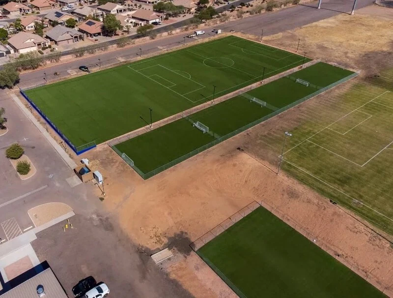 aerial photo of a group of synthetic turf fields installed in Phoenix AZ by Apex Turf. includes a full size soccer field, 4 training fields, and warm up areas. Green artificial turf is vibrant against the Arizona landscape.
