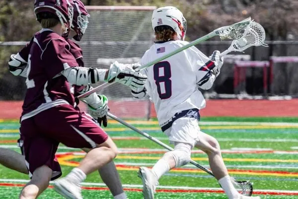 two lacrosse players in full grear running to score a goal